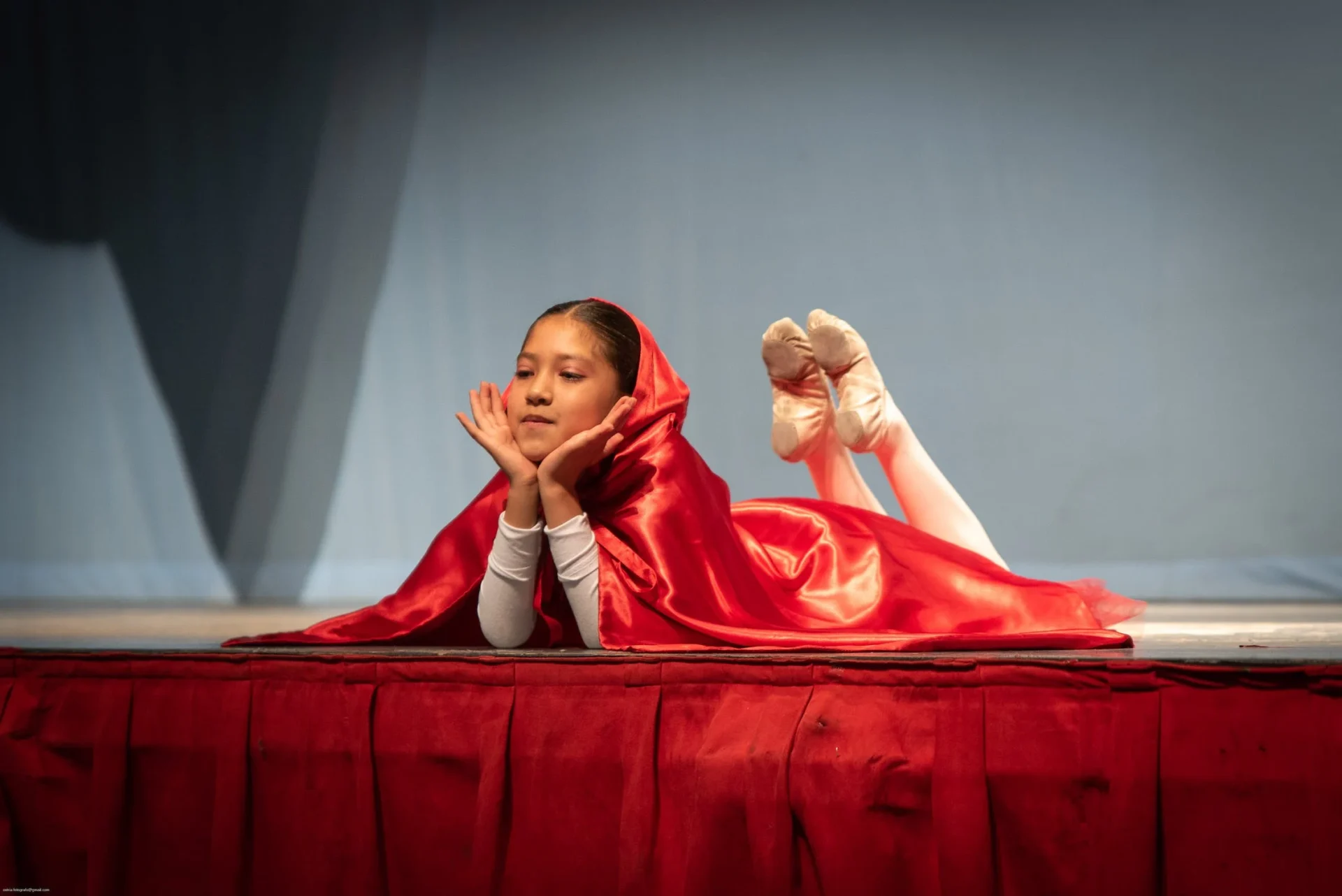 A woman in red is laying on the stage