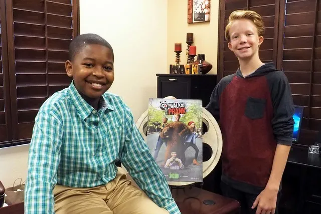 Two boys are posing for a picture in front of a video game.