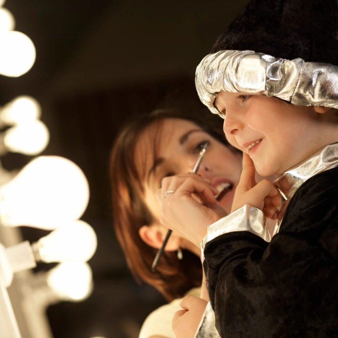 A woman and child in costume looking at a mirror.